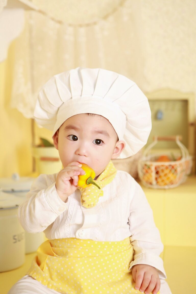 baby in chef hat eating a whole pear