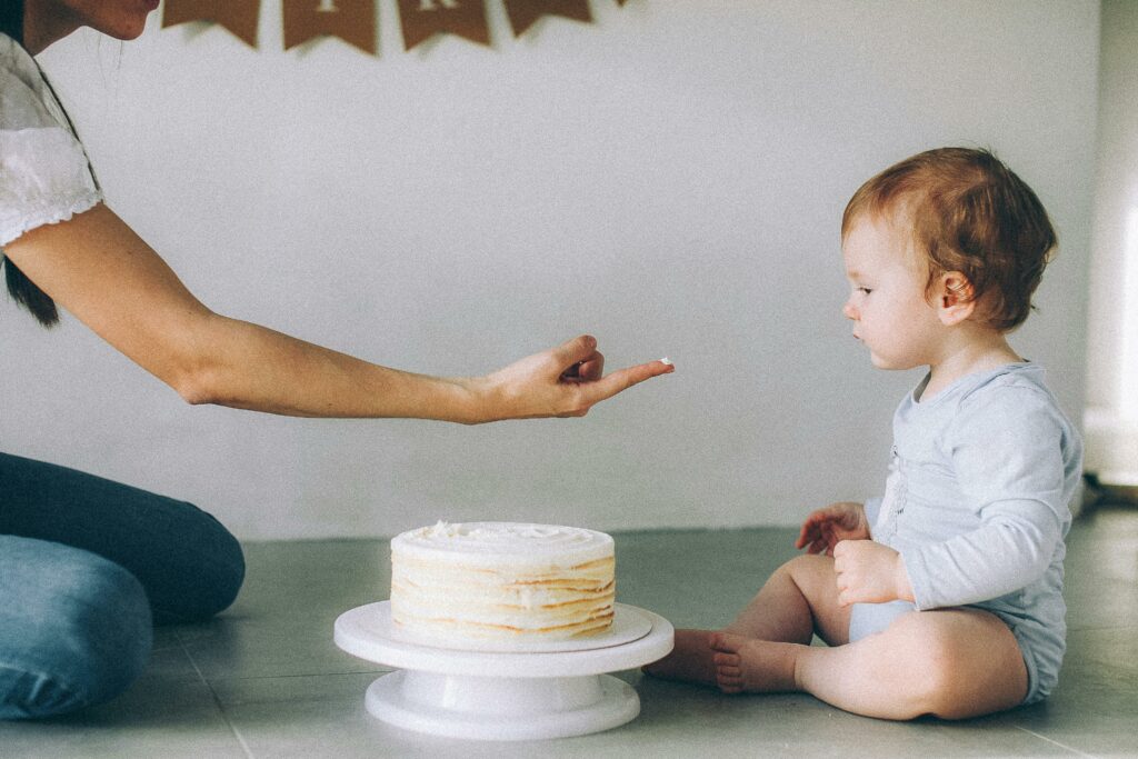 parent offering baby frosting from a cake